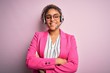 Young african american call center agent girl wearing glasses working using headset happy face smiling with crossed arms looking at the camera. Positive person.