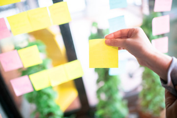 Business people hold sticky note for brainstorm idea at agile and scrum meeting at co working space in the city.Team work and small business concept