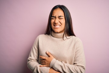 Canvas Print - Young beautiful asian woman wearing casual turtleneck sweater over pink background with hand on stomach because nausea, painful disease feeling unwell. Ache concept.