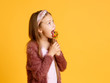 © Ilnur - Little girl enjoy lollipops during school break. Happy small schoolchild eat lollipops. Large swirl lollipops on sticks.