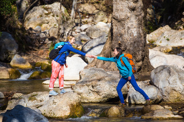 A woman helps her friend cross a mountain river.