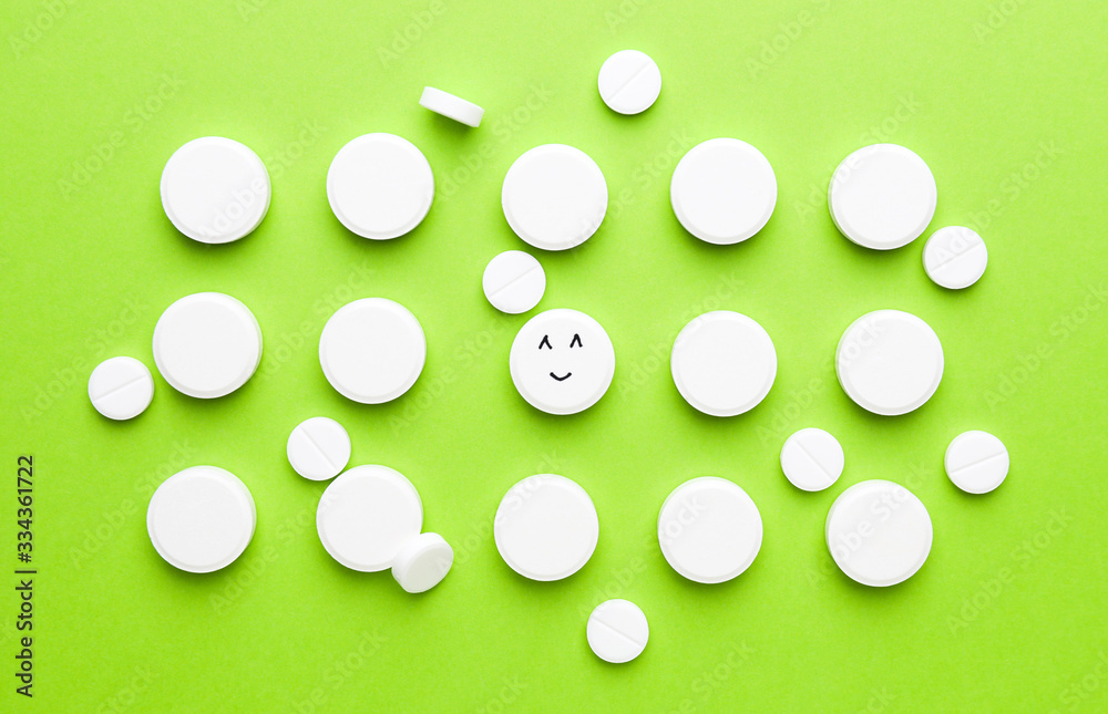 One pill with drawn happy face among white ones on color background