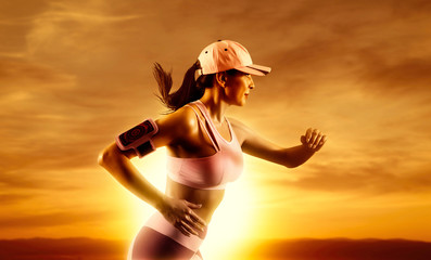 Wall Mural - Sporty young woman running on sunset background