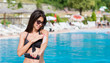 © boryanam - Beautiful Young Woman Applying Protective Sun Lotion to her Skin on a Pool Background
