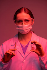 Poster - Pretty young nurse holding syringe and small bottle with vaccine against covid19