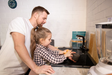 Wall Mural - Cute little girl washing her mug over sink with duster and dish washer