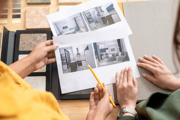Poster - Hands of young female interior designers looking through photos of modern rooms