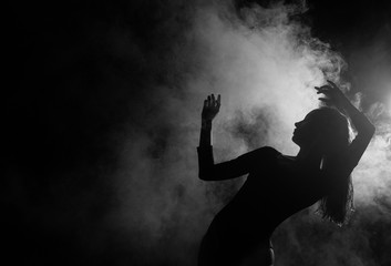 Female silhouette dancing in shadow and smoke