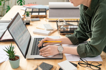 Wall Mural - Young creative female designer bending over desk in front of laptop