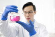 © pressmaster - Young Chinese man in whitecoat and protective gloves studying chemical substance