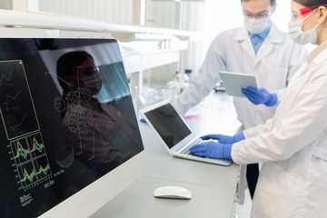 Computer screen with molecule model on background of two lab workers