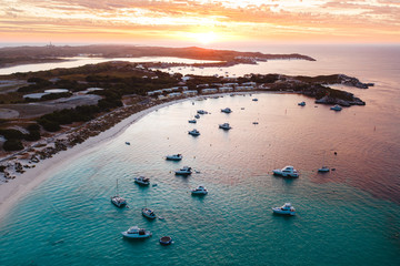 Wall Mural - Aerial drone shot of a magical sunset over Rottnest Island, Perth, Western Australia. Geordie Bay below with luxury boats and yachts. 