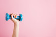© mellisandra - Womans hand holding blue dumbbell isolated on pink background. Equipment for home workout. Fitness and activity. Sport and healthy lifestyle concept. Copy space in right side