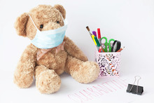 Cute Teddy Bear With Face Mask On His Mouth And Stationery On White Background. Quarantine.  Covid-19
