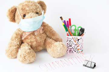 Cute teddy bear with face mask on his mouth and stationery on white background. Quarantine. Covid-19