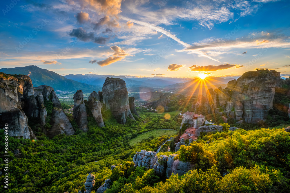 Sunset over monastery of Rousanou and Monastery of St. Nicholas Anapavsa in famous greek tourist destination Meteora in Greece on sunset with sun rays and lens flare - obrazy, fototapety, plakaty 