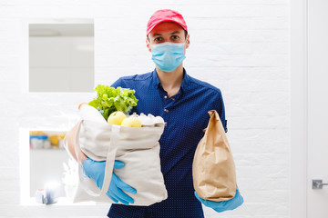 Courier's hands in latex white medical gloves deliver parcels in food packages to the door during the epidemic of coronovirus, COVID-19. Safe delivery of online orders during the epidemic.