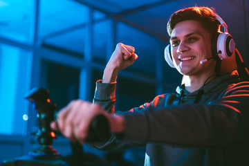 The gamer with headphones sitting and playing video games in the neon room