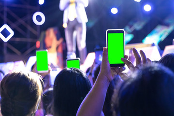 Wall Mural - Hands of audience crowd people taking photo with mobile smart phone with green screen in party concert.