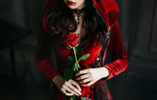 Close Up Portrait Silhouette Gothic Evil Woman Queen. Sexy Witch Face. Red Medieval Cape Dress Holiday Costume Hood. Princess Holding Rose In Hands. Vampire Makeup Lips Dripping Blood Halloween Image