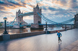 Fototapeta Londyn - Alone runner in empty streets of london in Coronavirus, Covid-19 quarantine time. Tower Bridge in background