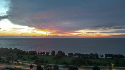 Wall Mural - Aerial sunrise timelapse as the sky erupts with pink, orange and yellow colored clouds and traffic begins to pick up along Lake Shore Drive in the Edgewater neighborhood of Chicago early morning.