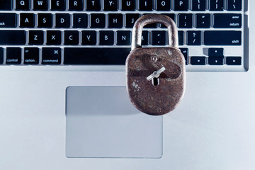 Close up laptop computer with old solid lock as symbol of the access controls and security network and software