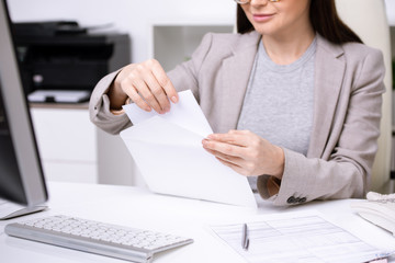 Poster - Hands of young businesswoman or banker putting folded paper into white envelope