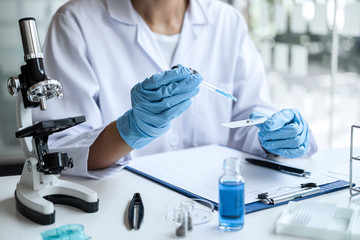 Scientist or medical in lab coat holding test tube with reagent, mixing reagents in glass flask, glassware containing chemical liquid, laboratory research and testing of Microscope