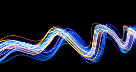 Wall Mural - Blue and gold light painting photography, long exposure photo of metallic gold and electric blue streaks of vibrant color against a black background