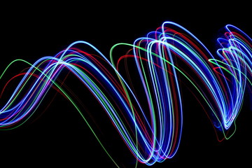 Wall Mural - Multi color light painting photography, long exposure photo of electric blue, red and green, ripples and waves of vibrant color in parallel lines against a black background