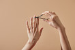 Partial view of woman doing manicure with cuticle nipper isolated on beige