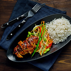 Wall Mural - Asian- style chicken with savory and sweet teriyaki sauce, rice, sesame, salad, edamame, lemon and sweet chili sauce on a wooden table with a blue tablecloth. Top view, directly above.