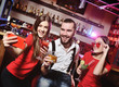 © Evgeniy Kalinovskiy - Time Selfie. A group of friends at a party in a nightclub clink glasses with alcoholic beverages. Happy young people with cocktails in the pub.