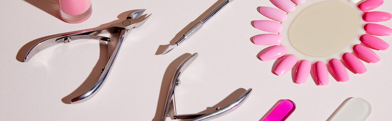 Wall Mural - High angle view of samples of nail polish with manicure instruments on white, panoramic shot