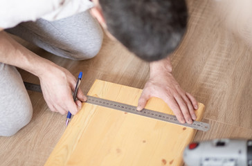 person using metal ruler to measure size of  drilling hole to attach console. repairs on their hands, work at home concept