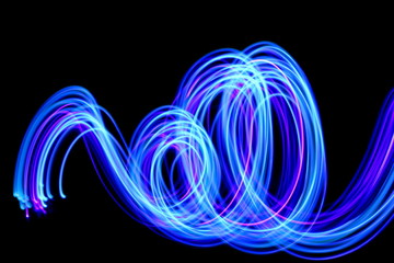 Long exposure photograph of neon blue streaks of light in an abstract swirl, parallel lines pattern against a black background. Light painting photography.