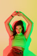 © LIGHTFIELD STUDIOS - top view of sensual, fashionable girl looking at camera while lying on yellow background with green and red shadows