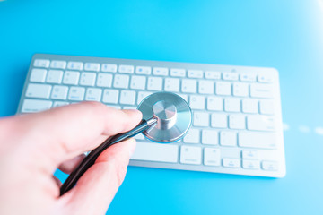 Computer system health or auditing - Stethoscope over a computer keyboard toned in blue