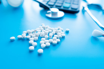 pills and medicines under a magnifying glass next to a medical stethoscope. The concept of health and responsible use of medicines, vitamins and various supplements