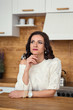 © Tatsiana - close portrait of a dreaming attractive stylish woman in a white sweater on one shoulder in the kitchen behind the counter