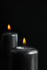 Wall Mural - Two black candles burning at night. Focus on single candle in foreground.