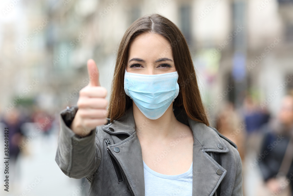 Happy woman with mask gesturing thumbs up - obrazy, fototapety, plakaty 