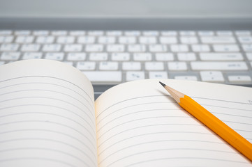 Online learning concept. There are a lined notebook and a yellow pencil on the keyboard of the laptop.