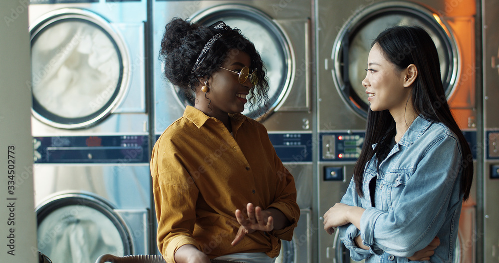 Mixed-races stylish young girls best friends talking and sharing ...