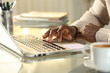 © PheelingsMedia - Black man hands using touchpad on laptop at home