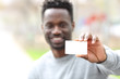 © PheelingsMedia - Happy black man showing blank credit card in the park