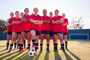 Portrait Of Smiling Womens Football Team Training For Soccer Match On Outdoor Astro Turf Pitch