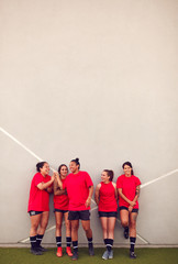 Wall Mural - Graphic Shot Of Womens Football Team Leaning Against Wall Whilst Training For Soccer Match