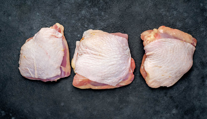 Raw chicken thighs with spices on a stone background